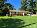 Well-maintained home with green lawn, landscaping, brick accents, and a covered carport, nestled among mature trees at 708 East St # 89, Albemarle, NC 28001
