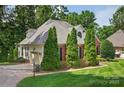 Brick home with attached garage surrounded by mature trees and lush green lawn at 803 Woodmoore Ln, Kannapolis, NC 28081