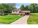 Inviting home with lush green lawn, convenient carport, and mature trees, offering a blend of comfort and charm at 103 Little Forest Ln, Statesville, NC 28625