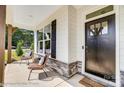 Inviting front porch with stone accents, wicker seating, and a stylish black front door at 111 Summerhill Dr # 2, Mooresville, NC 28115