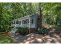 Charming home with front porch, brick chimney, and mature landscaping, surrounded by lush greenery and trees at 1118 Brookwood Dr, Stanley, NC 28164