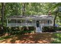 Charming home with a welcoming front porch, lush landscaping, and inviting curb appeal amidst a leafy surrounding at 1118 Brookwood Dr, Stanley, NC 28164