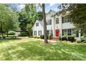 Beautiful two-story home with lush lawn, red front door, and surrounded by mature trees at 11624 Crossroads Pl, Concord, NC 28025