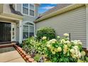 Close-up of the front entrance with colorful flowers, green bushes, and brick accents, creating an inviting entry at 2026 Rosewater Ln, Indian Trail, NC 28079