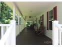 Long covered porch featuring rocking chairs, windows, and dark wooden floors at 220 Singing Pine Dr, Clover, SC 29710