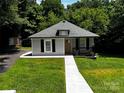A cozy home featuring a newly installed walkway, complimented by lush greenery and mature trees at 305 E Henry St, Belmont, NC 28012