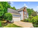 View of the home's side facade showing the garage, brick accents, and manicured greenery at 5238 Downing Creek Dr, Charlotte, NC 28269