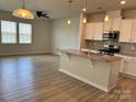 Open-concept kitchen and living area with a center island, white cabinets, and stainless steel appliances at 5337 Orchid Bloom Dr, Indian Land, SC 29707