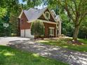 Side view of the home featuring a three-car garage and lush greenery at 610 Hampshire Hill Rd, Matthews, NC 28105