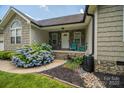 Inviting front porch with stone facade, blue chairs, and vibrant hydrangeas creating a warm entrance at 104 Nottingham Dr, Maiden, NC 28650