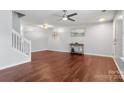 Open living room with hardwood floors, a ceiling fan, and a decorative wall design at 11023 Kinston Ridge Pl, Charlotte, NC 28273