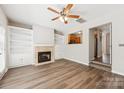 Open living room with hardwood floors, fireplace, built-in shelving, ceiling fan, and view into the kitchen at 17431 Tuscany Ln, Cornelius, NC 28031