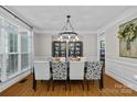 A dining room with a dark wood table, white trim, wood floors, and a large window with black and white floral print chairs at 3020 Waxhaw Crossing Dr, Waxhaw, NC 28173