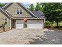 Three car garage showcases white doors, neutral siding, and flags for added curb appeal at 3020 Waxhaw Crossing Dr, Waxhaw, NC 28173