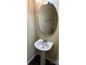 Cozy powder room featuring a pedestal sink, an oval mirror, and neutral walls at 6130 Sid Crane Dr, Charlotte, NC 28216
