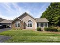 Charming home exterior with stone accents, manicured shrubs, and a lush green lawn on a sunny day at 6811 Ledgestone Pl, Charlotte, NC 28227