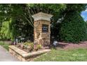 Auburn Place stone monument entrance sign complemented by flowering plants and American flags at 8409 Darcy Hopkins Dr, Charlotte, NC 28277