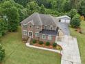 Beautiful brick home with a well-manicured lawn, mature trees, and a detached two-car garage in the background at 9450 Surface Hill Rd, Mint Hill, NC 28227