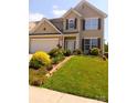 Two-story home with beautiful landscaping, a green lawn, flowers, and stone edging under a clear blue sky at 115 Morrocroft Ln, Mooresville, NC 28117
