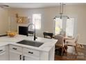 Modern kitchen featuring white cabinets, a marble countertop, and an adjacent dining area with stylish furniture at 115 Morrocroft Ln, Mooresville, NC 28117