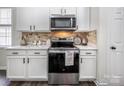 Stylish kitchen features white cabinetry, stainless steel appliances, and a decorative backsplash at 115 Morrocroft Ln, Mooresville, NC 28117