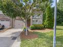 Well-manicured front yard with mature tree, two-car garage, and stone accents on the facade at 1169 Stuarts Landing Dr, Cramerton, NC 28032