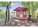 A cute red storage shed with a front porch, nestled among the trees at 16509 Kimbolten Dr, Huntersville, NC 28078