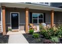 Charming covered porch with seating and meticulous landscaping provides a cozy outdoor space at 205 Spring Creek Dr, Mount Holly, NC 28120