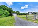 View of a house with a gravel driveway and a large grassy yard, showcasing the property's curb appeal and natural setting at 237 Mariposa Rd, Stanley, NC 28164