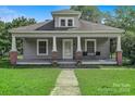 Cozy home featuring a welcoming front porch with classic column details and lush lawn at 2417 Statesville Blvd, Salisbury, NC 28147