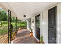 Inviting front porch with wood flooring, wrought iron posts, and decorative potted plants at 402 Ford St, Kannapolis, NC 28083