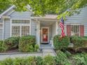 Charming front porch with an American flag, bench, red door, and manicured shrubs at the home's entrance at 4801 Pennant Pl, Charlotte, NC 28212