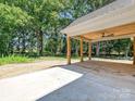 Large covered backyard patio with wooden pillars, tongue and groove ceiling, fan, and tranquil views of wooded property at 501 E Cj Thomas Rd # 1, Monroe, NC 28110
