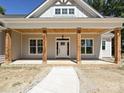 Inviting front porch featuring wood pillars, wood ceiling, a hanging light, and a modern white front door at 501 E Cj Thomas Rd # 1, Monroe, NC 28110