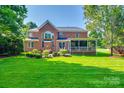 Expansive backyard with lush lawn, mature trees, brick patio, and screened porch at 8102 Bergen Ct, Waxhaw, NC 28173