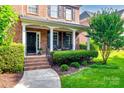 Welcoming front porch with black door, brick steps, and decorative landscaping at 8102 Bergen Ct, Waxhaw, NC 28173