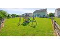 Large backyard with lush green grass and a vibrant playset under a clear blue sky at 8312 Compton Acres Ln, Waxhaw, NC 28173