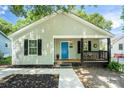Charming home with a covered front porch featuring black accents, an inviting blue door and landscaped yard at 909 Gibbons St, Gastonia, NC 28052