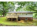 Back exterior of a split-level house featuring a wooden deck, gray siding, and a brick foundation at 1309 Poplar Cir, Newton, NC 28658