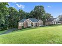 Beautiful brick home with a lush green lawn and a driveway, nestled among mature trees at 1622 Brookstone Dr, Hickory, NC 28602