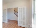 Bright living space showcasing wood floors, a window, and open French doors to the staircase at 1821 Augustine St, Monroe, NC 28112