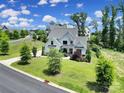 A daytime aerial shot of a beautifully landscaped home on a lush green lot with mature trees and a winding street at 2148 Nims Village Dr, Fort Mill, SC 29715