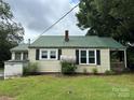 Back exterior view of home with metal roof and green grass at 30497 Orchard Ln, Albemarle, NC 28001