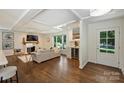 Bright living room with a coffered ceiling, hardwood floors, a fireplace with a wood mantle, and a built-in bar area with a wine cooler at 3165 Pendleton Ave, Charlotte, NC 28210