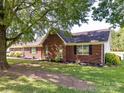 Picture of a red brick home with a large tree in the foreground on a large lot at 5105 Hampton Meadows Rd, Monroe, NC 28110