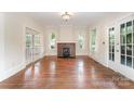 Spacious living room featuring hardwood floors, a brick fireplace, and ample natural light at 6206 Hunter Ave, Charlotte, NC 28262