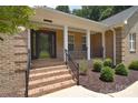 Inviting covered front porch with brick columns, brick steps and mature landscaping at 9117 Castle Garden Ln, Charlotte, NC 28215