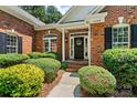 Close-up of a welcoming brick home entrance with black door and manicured shrubs at 1399 Verdict Ridge Dr, Denver, NC 28037