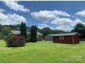Lush green backyard with a red storage shed and mature trees, offering privacy and space at 1901 Taylor Dr, Gastonia, NC 28052