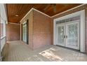 A private, covered porch featuring classic brickwork, perfect for enjoying the outdoors year-round with ceiling fans at 320 Magnolia St, Davidson, NC 28036